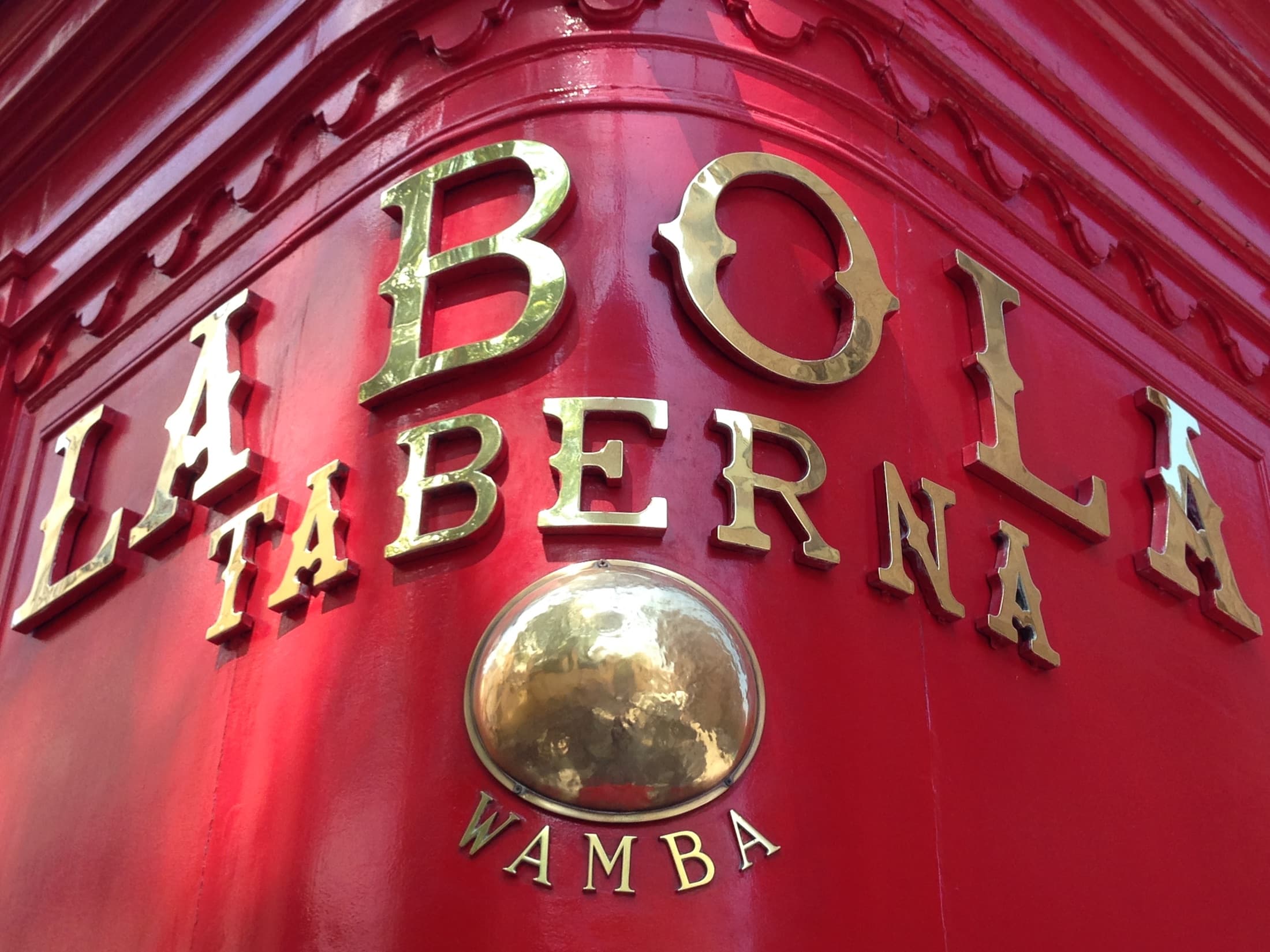 Rótulo dorado de Taberna La Bola sobre su fachada roja