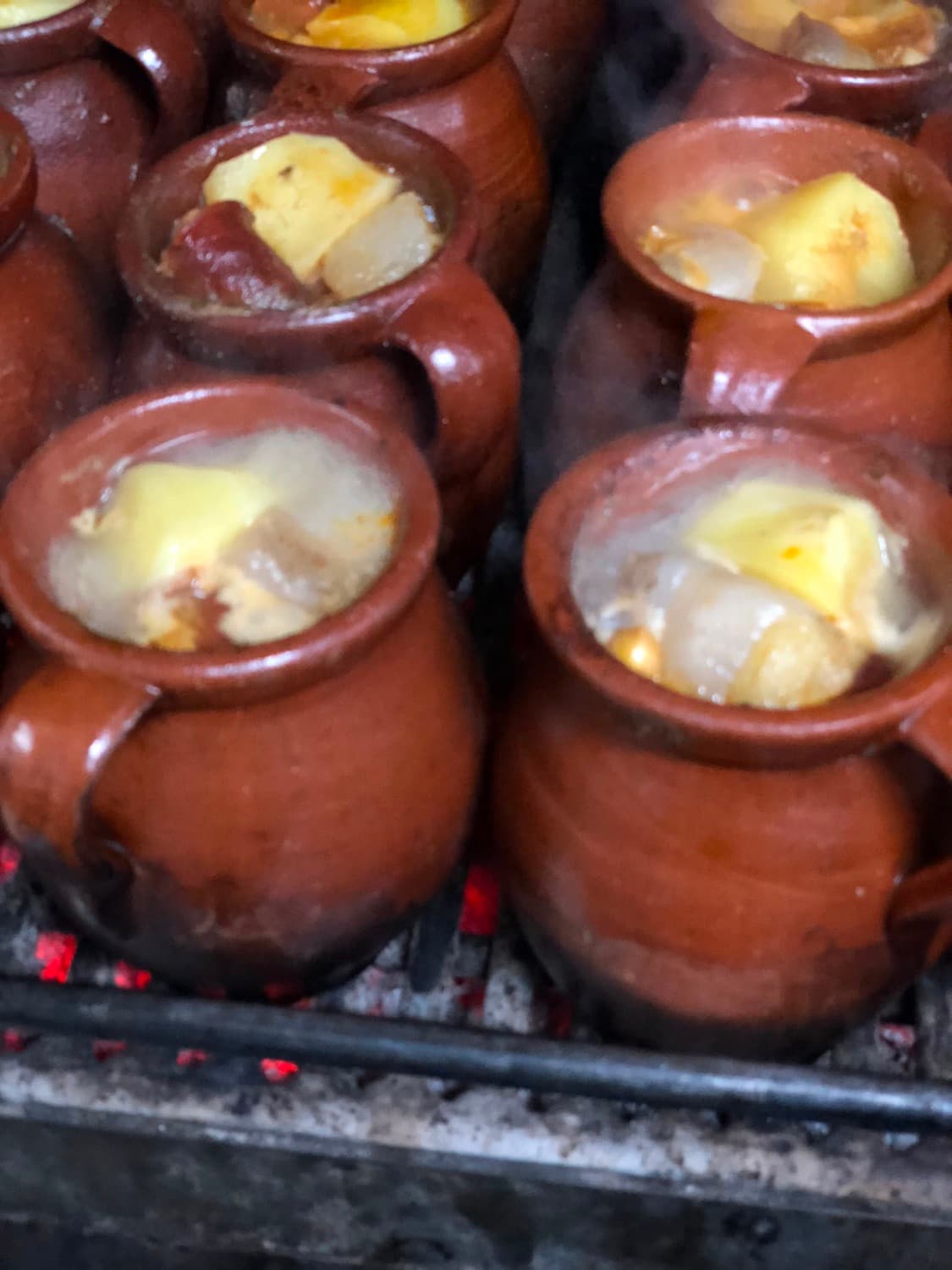 Pucheros de barro con cocido madrileño sobre carbón de encina